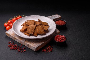 Tohumlar, tanecikler, tuz, baharatlar ve çimento kaplı ev yapımı çıtır kahverengi ekmek cipsleri.