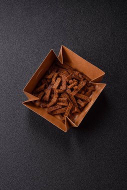 Koyu beton arka planda tohum ve tahıllı, tuzlu, baharatlı ve otlu ev yapımı kahverengi ekmek krakerleri veya kızarmış ekmekler.