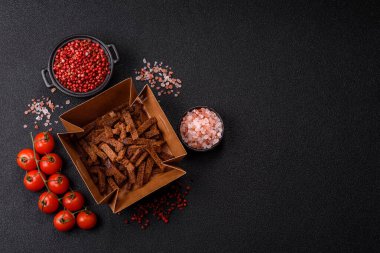 Koyu beton arka planda tohum ve tahıllı, tuzlu, baharatlı ve otlu ev yapımı kahverengi ekmek krakerleri veya kızarmış ekmekler.