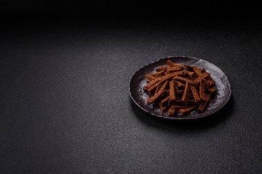 Koyu beton arka planda tohum ve tahıllı, tuzlu, baharatlı ve otlu ev yapımı kahverengi ekmek krakerleri veya kızarmış ekmekler.