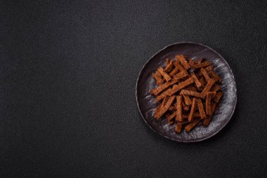 Koyu beton arka planda tohum ve tahıllı, tuzlu, baharatlı ve otlu ev yapımı kahverengi ekmek krakerleri veya kızarmış ekmekler.