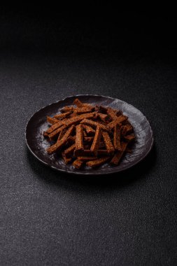 Koyu beton arka planda tohum ve tahıllı, tuzlu, baharatlı ve otlu ev yapımı kahverengi ekmek krakerleri veya kızarmış ekmekler.