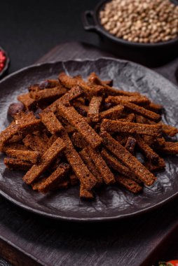 Koyu beton arka planda tohum ve tahıllı, tuzlu, baharatlı ve otlu ev yapımı kahverengi ekmek krakerleri veya kızarmış ekmekler.