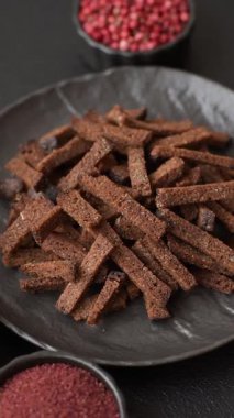 Koyu beton arka planda tohum ve tahıllı, tuzlu, baharatlı ve otlu ev yapımı kahverengi ekmek krakerleri veya kızarmış ekmekler.