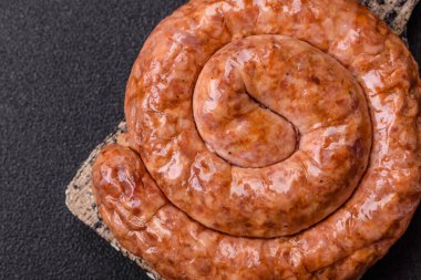 Salyangoz ya da spiral şeklinde nefis ev yapımı sosis. Koyu beton arka planda tuz ve baharatlar var.