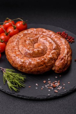 Salyangoz ya da spiral şeklinde nefis ev yapımı sosis. Koyu beton arka planda tuz ve baharatlar var.