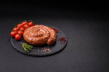 Salyangoz ya da spiral şeklinde nefis ev yapımı sosis. Koyu beton arka planda tuz ve baharatlar var.