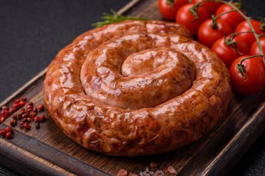 Salyangoz ya da spiral şeklinde nefis ev yapımı sosis. Koyu beton arka planda tuz ve baharatlar var.