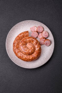 Salyangoz ya da spiral şeklinde nefis ev yapımı sosis. Koyu beton arka planda tuz ve baharatlar var.