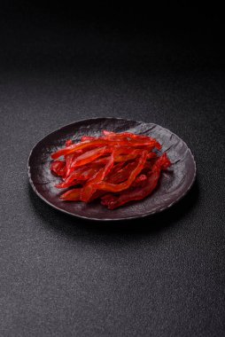 Kurutulmuş tavuk dilimleri, kurutulmuş et, kiraz ya da erik aromalı, tuzlu ve baharatlı koyu beton arka planda.