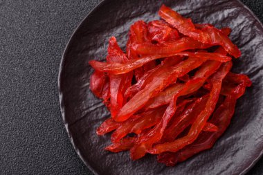 Kurutulmuş tavuk dilimleri, kurutulmuş et, kiraz ya da erik aromalı, tuzlu ve baharatlı koyu beton arka planda.