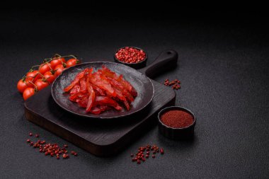 Kurutulmuş tavuk dilimleri, kurutulmuş et, kiraz ya da erik aromalı, tuzlu ve baharatlı koyu beton arka planda.