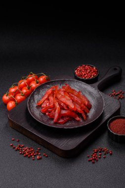 Kurutulmuş tavuk dilimleri, kurutulmuş et, kiraz ya da erik aromalı, tuzlu ve baharatlı koyu beton arka planda.