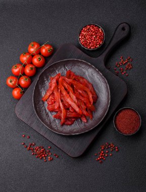 Kurutulmuş tavuk dilimleri, kurutulmuş et, kiraz ya da erik aromalı, tuzlu ve baharatlı koyu beton arka planda.