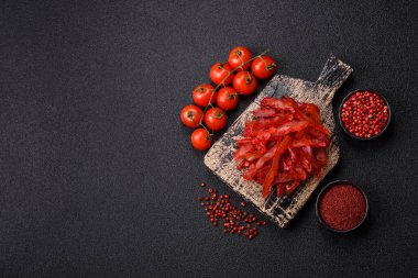 Kurutulmuş tavuk dilimleri, kurutulmuş et, kiraz ya da erik aromalı, tuzlu ve baharatlı koyu beton arka planda.