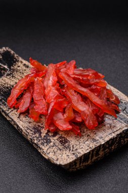 Kurutulmuş tavuk dilimleri, kurutulmuş et, kiraz ya da erik aromalı, tuzlu ve baharatlı koyu beton arka planda.