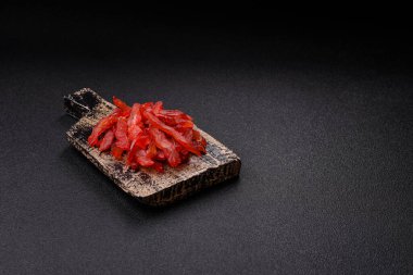 Kurutulmuş tavuk dilimleri, kurutulmuş et, kiraz ya da erik aromalı, tuzlu ve baharatlı koyu beton arka planda.