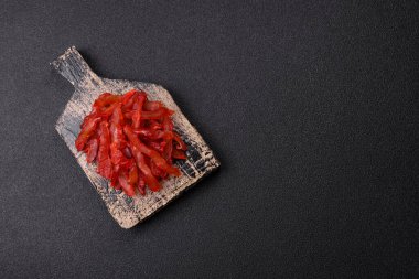 Kurutulmuş tavuk dilimleri, kurutulmuş et, kiraz ya da erik aromalı, tuzlu ve baharatlı koyu beton arka planda.