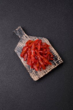 Kurutulmuş tavuk dilimleri, kurutulmuş et, kiraz ya da erik aromalı, tuzlu ve baharatlı koyu beton arka planda.