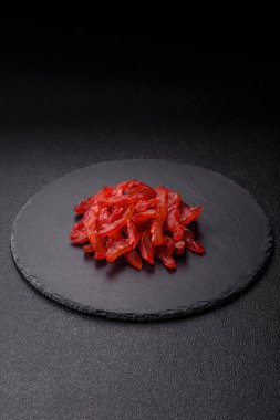 Kurutulmuş tavuk dilimleri, kurutulmuş et, kiraz ya da erik aromalı, tuzlu ve baharatlı koyu beton arka planda.