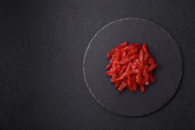 Kurutulmuş tavuk dilimleri, kurutulmuş et, kiraz ya da erik aromalı, tuzlu ve baharatlı koyu beton arka planda.