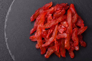 Kurutulmuş tavuk dilimleri, kurutulmuş et, kiraz ya da erik aromalı, tuzlu ve baharatlı koyu beton arka planda.