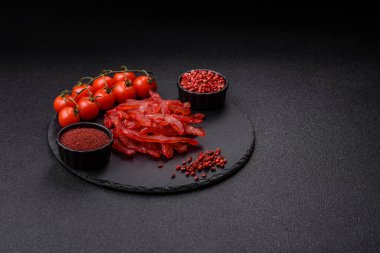 Kurutulmuş tavuk dilimleri, kurutulmuş et, kiraz ya da erik aromalı, tuzlu ve baharatlı koyu beton arka planda.