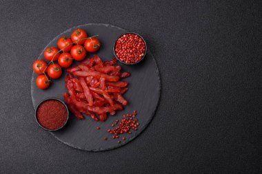 Kurutulmuş tavuk dilimleri, kurutulmuş et, kiraz ya da erik aromalı, tuzlu ve baharatlı koyu beton arka planda.