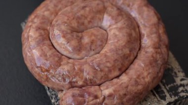 Salyangoz ya da spiral şeklinde nefis ev yapımı sosis. Koyu beton arka planda tuz ve baharatlar var.