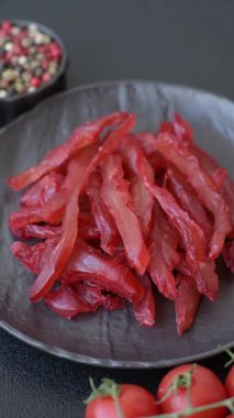 Kurutulmuş tavuk dilimleri, kurutulmuş et, kiraz ya da erik aromalı, tuzlu ve baharatlı koyu beton arka planda.