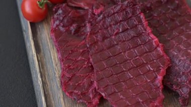 Kurutulmuş sığır eti dilimleri, kurutulmuş et, kiraz veya erik aromalı, tuz ve baharatlar koyu beton arka planda.