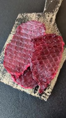 Kurutulmuş sığır eti dilimleri, kurutulmuş et, kiraz veya erik aromalı, tuz ve baharatlar koyu beton arka planda.