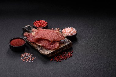 Kurutulmuş et, tuz ve baharatla birlikte koyu beton arka planda dilimler.