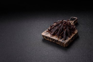 Kurutulmuş at eti ya da koyu beton arka planda tuz ve baharatlı biftek dilimleri.