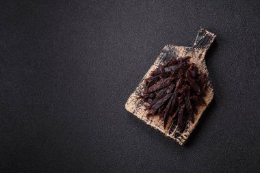 Kurutulmuş at eti ya da koyu beton arka planda tuz ve baharatlı biftek dilimleri.