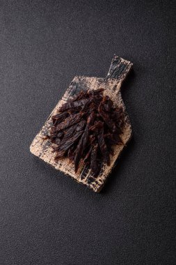 Kurutulmuş at eti ya da koyu beton arka planda tuz ve baharatlı biftek dilimleri.