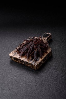 Kurutulmuş at eti ya da koyu beton arka planda tuz ve baharatlı biftek dilimleri.