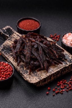 Kurutulmuş at eti ya da koyu beton arka planda tuz ve baharatlı biftek dilimleri.