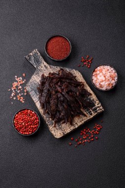 Kurutulmuş at eti ya da koyu beton arka planda tuz ve baharatlı biftek dilimleri.