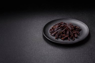 Kurutulmuş at eti ya da koyu beton arka planda tuz ve baharatlı biftek dilimleri.