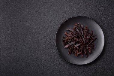 Kurutulmuş at eti ya da koyu beton arka planda tuz ve baharatlı biftek dilimleri.