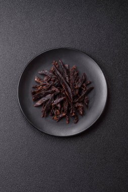 Kurutulmuş at eti ya da koyu beton arka planda tuz ve baharatlı biftek dilimleri.