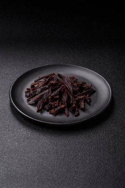 Kurutulmuş at eti ya da koyu beton arka planda tuz ve baharatlı biftek dilimleri.