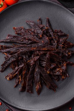 Kurutulmuş at eti ya da koyu beton arka planda tuz ve baharatlı biftek dilimleri.