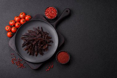 Kurutulmuş at eti ya da koyu beton arka planda tuz ve baharatlı biftek dilimleri.