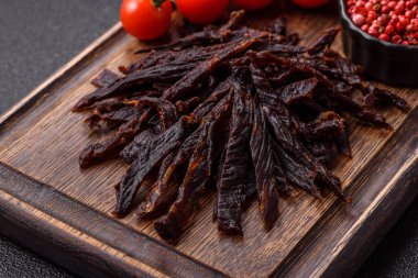 Kurutulmuş at eti ya da koyu beton arka planda tuz ve baharatlı biftek dilimleri.