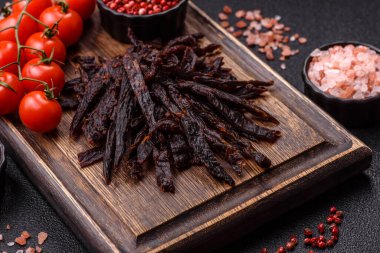 Kurutulmuş at eti ya da koyu beton arka planda tuz ve baharatlı biftek dilimleri.