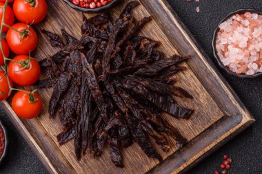 Kurutulmuş at eti ya da koyu beton arka planda tuz ve baharatlı biftek dilimleri.