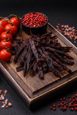 Kurutulmuş at eti ya da koyu beton arka planda tuz ve baharatlı biftek dilimleri.