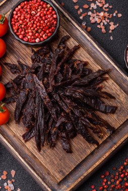 Kurutulmuş at eti ya da koyu beton arka planda tuz ve baharatlı biftek dilimleri.